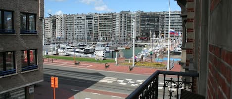 A view of a marina with boats, a pedestrian crossing, and high-rise buildings in the background.