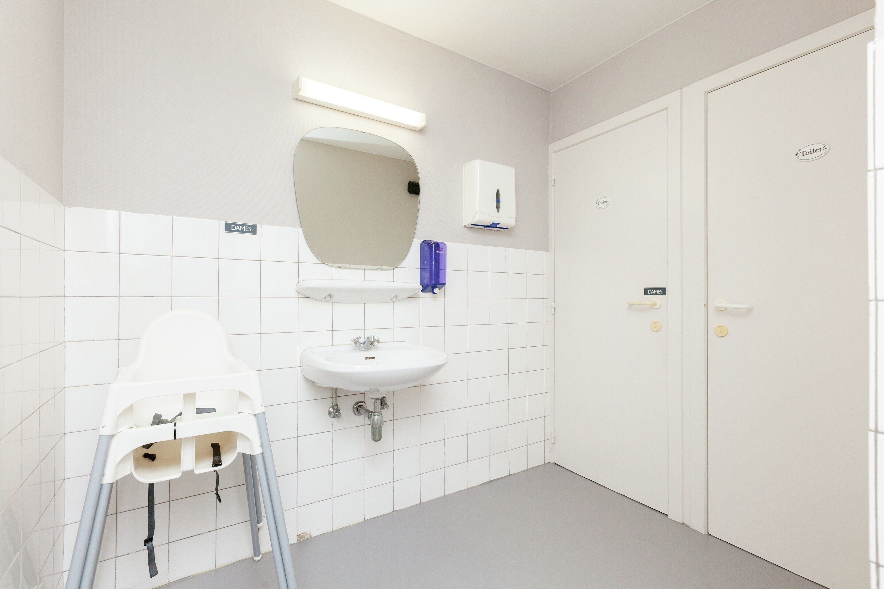 A bathroom with a white sink, mirror, and toilet.