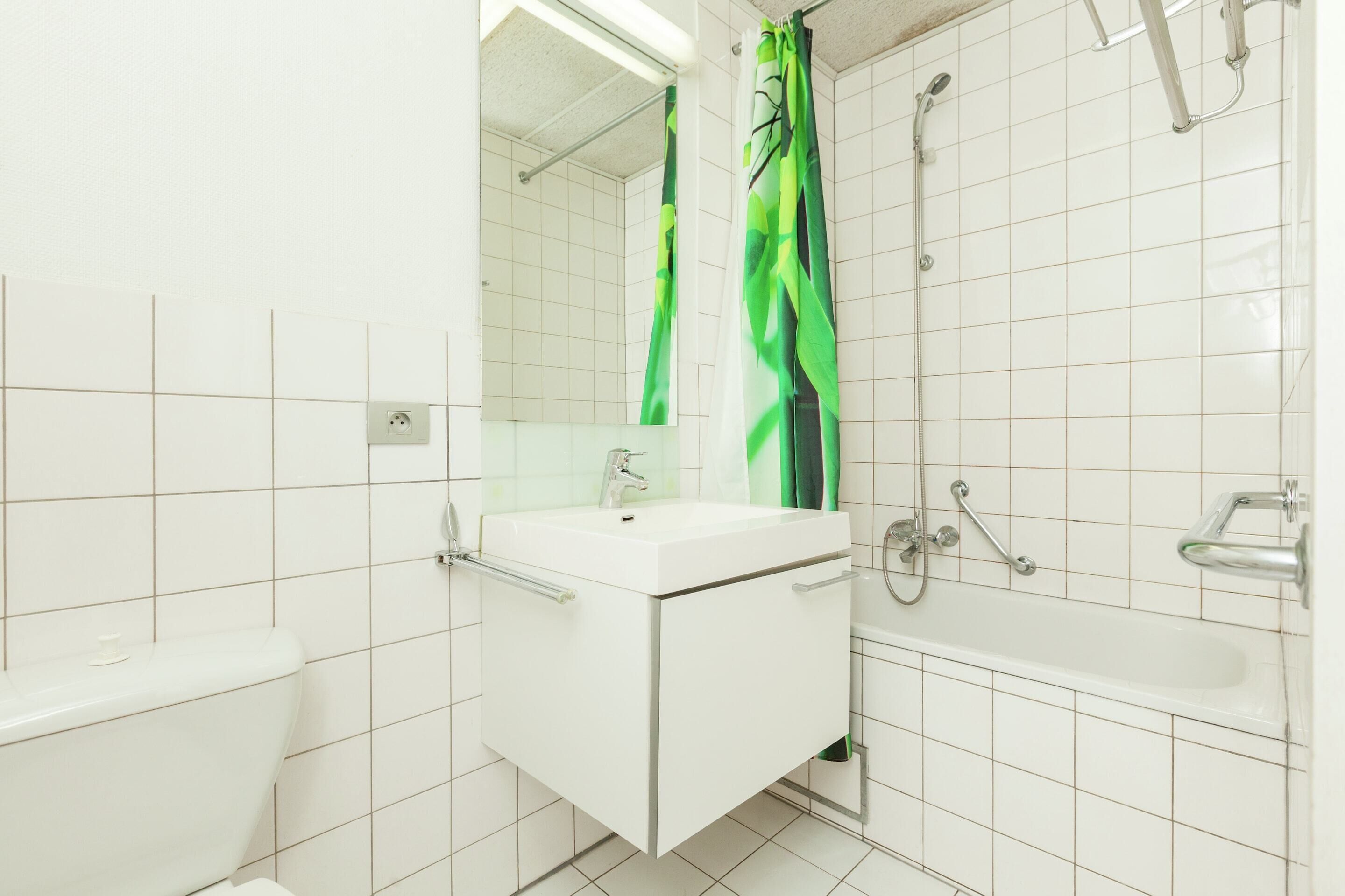 A bathroom with a white sink, mirror, and shower area.