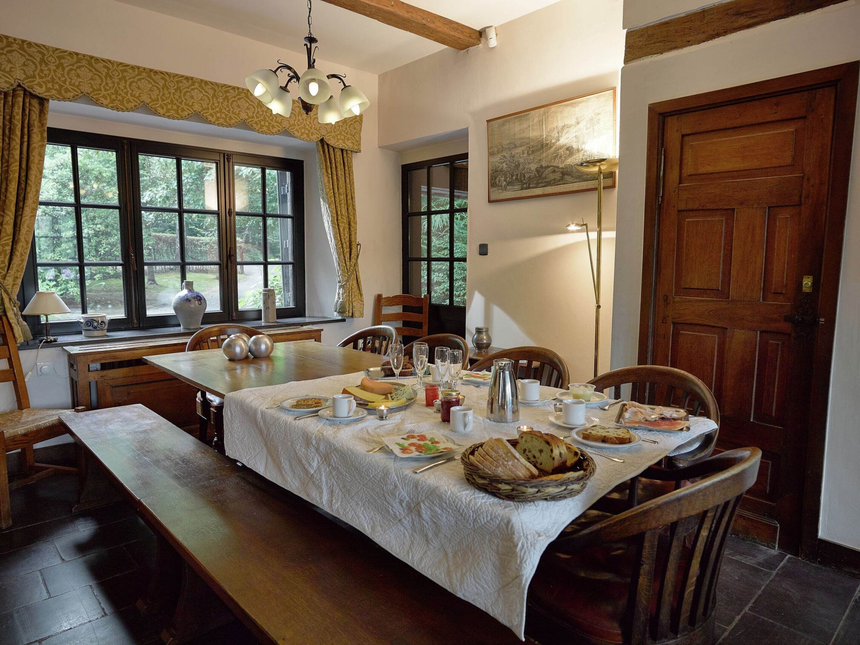 A dining area with a long table set for a meal, surrounded by wooden chairs.