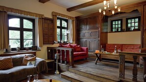 A traditional room with wooden beams, a red sofa, a dining table with wine, and a staircase. - Spacious Villa in Liege (Spa)