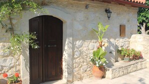 A stone building with a large wooden door, potted plants, and a tiled roof. - Quaint Holiday Home in Pasalites with Garden near Perama (Mylopotamos)