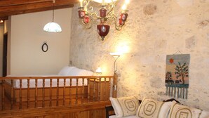 A cozy room with a wooden bed, a sofa with patterned cushions, a stone wall, and a decorative painting. - Quaint Holiday Home in Pasalites with Garden near Perama (Mylopotamos)