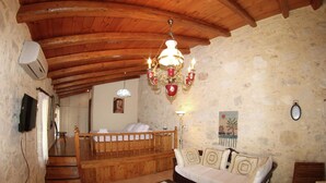 A rustic room with a wooden ceiling, a bed with a wooden headboard, a sofa, a coffee table, and a wall-mounted clock. - Quaint Holiday Home in Pasalites with Garden near Perama (Mylopotamos)