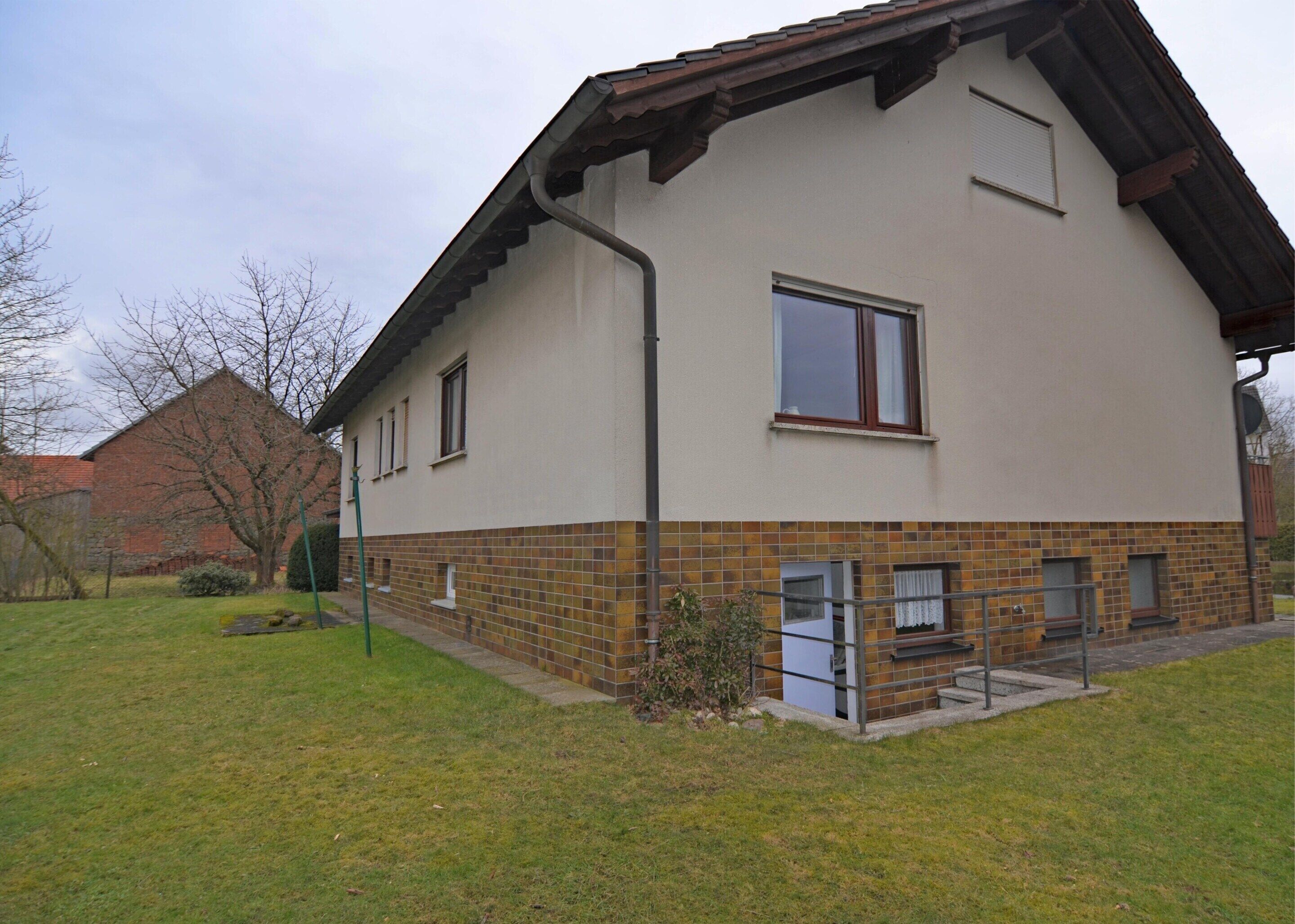 Une maison à deux étages dont la partie inférieure est recouverte de carreaux et qui possède un toit en pente.