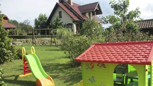 A playground with a slide and a playhouse with chairs inside.