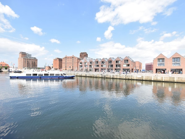 A waterfront area with a row of brick buildings, a blue boat docked at the pier, and a clear sky. - Tolles Ferienhaus in Wismar fur 8 Personen (Wismar)