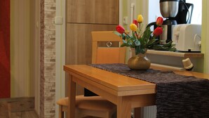 A wooden table with a vase of tulips, a coffee maker, and a toaster on a kitchen counter.
