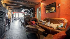 A cozy lounge area with leather sofas, a bar in the background, and a stone wall. - Quaint Apartment in Sensenruth With Terrace (Bouillon)