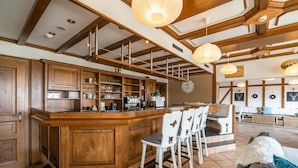 A spacious bar area with wooden cabinetry, a central bar counter, and white bar stools. - Gouvy Getaway Holiday Home (Gouvy)