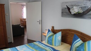 Une chambre à coucher avec un lit, des oreillers, une table de chevet et un tableau représentant des fleurs accroché au mur.