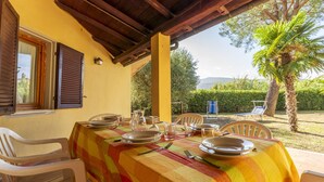An outdoor dining area with a table set for four, surrounded by chairs, under a wooden pergola. - Seaside Comfort in Giannella (Orbetello)