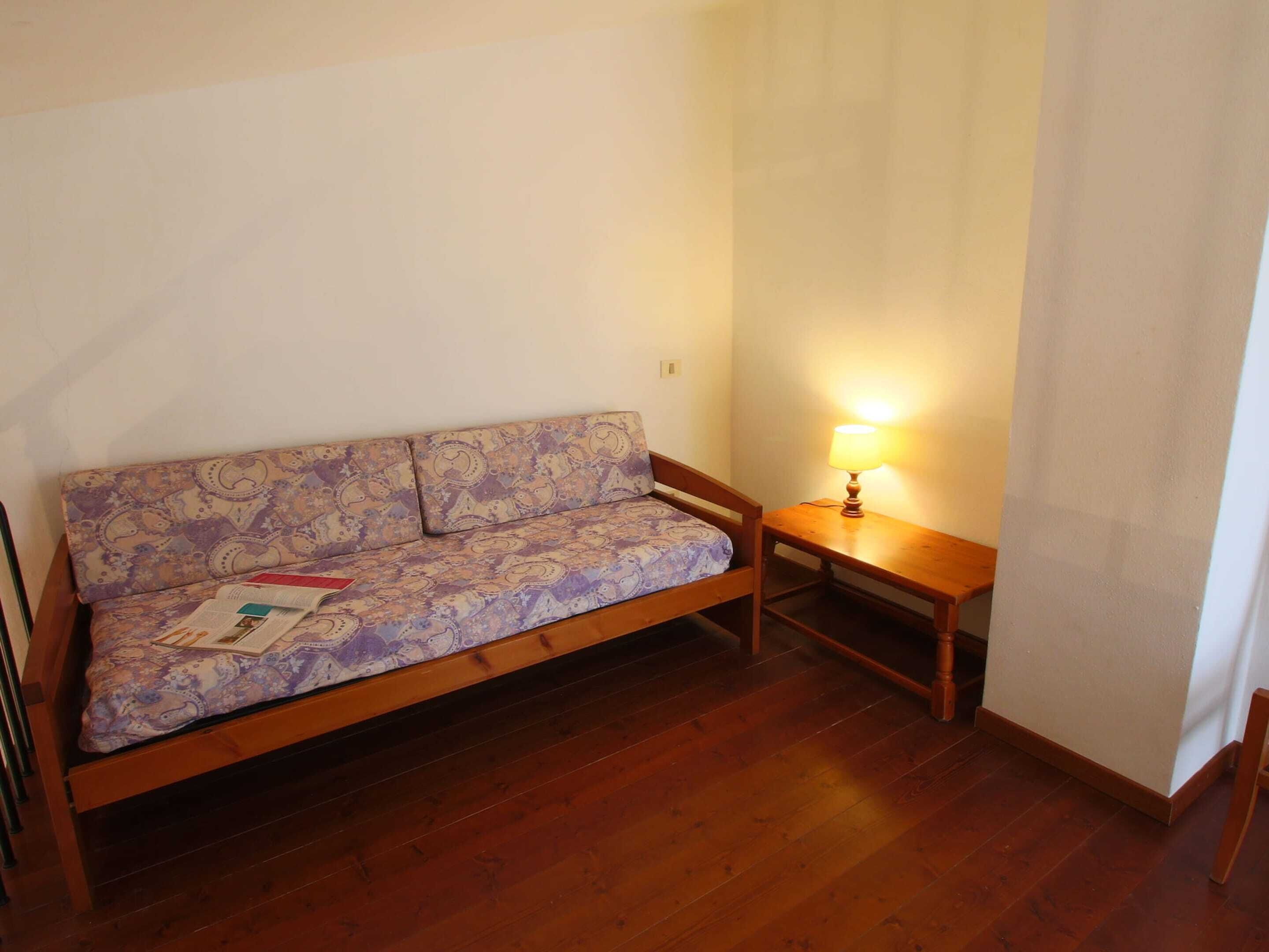 Une petite pièce avec un canapé en bois, une table en bois et une lampe.