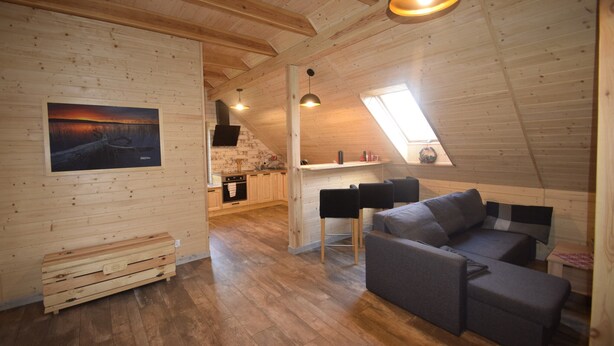 Un acogedor espacio tipo loft con detalles de madera, un sofá gris y un banco de madera.