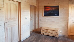 Un interior de madera con una puerta grande, un banco y un cuadro en la pared.