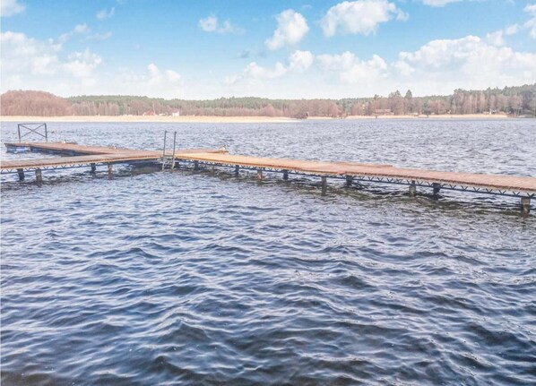 A wooden pier extending into a calm lake with a forested shoreline in the background. - Holiday Home in Skrzynia With Terrace (gmina Osiek)