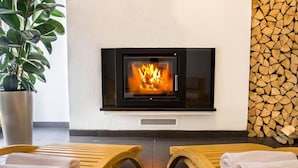 A room with a fireplace, two wooden lounge chairs, and a potted plant. - Secluded Holiday Home with Hot Tub in Kozji Vrh (Cabar)