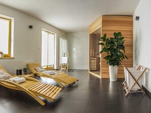 A modern spa room with wooden loungers, a large potted plant, and a glass partition. - Secluded Holiday Home with Hot Tub in Kozji Vrh (Cabar)