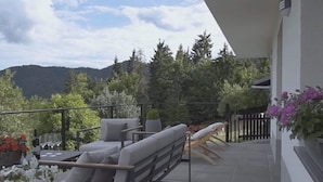 A balcony with a sofa, a dining table, and potted plants. - Secluded Holiday Home with Hot Tub in Kozji Vrh (Cabar)