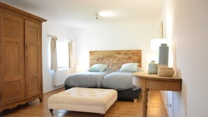 A bedroom with two beds, a wooden wardrobe, a bedside table with a lamp, and a window with curtains. - Peaceful Holiday Home (Rochefort)