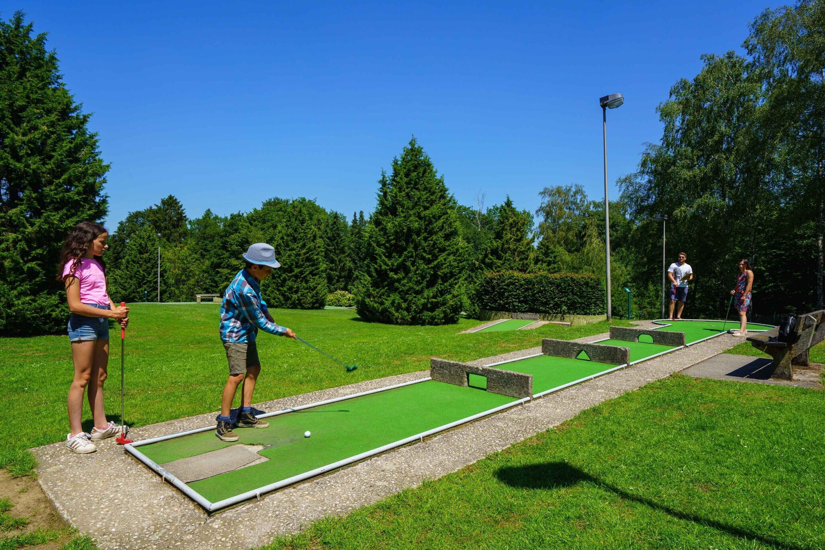 A croquet field with players and a clear sky.