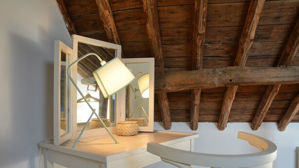 A room with a wooden ceiling, a white desk with a mirror, a lamp, and a woven basket. - Peaceful Holiday Home (Rochefort)