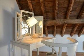 A room with a wooden ceiling, a white desk with a mirror, a lamp, and a woven basket. - Peaceful Holiday Home (Rochefort)