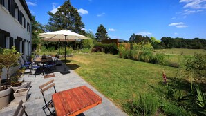 An outdoor patio with a table and chairs, a large umbrella, and a grassy lawn. - Peaceful Holiday Home (Rochefort)