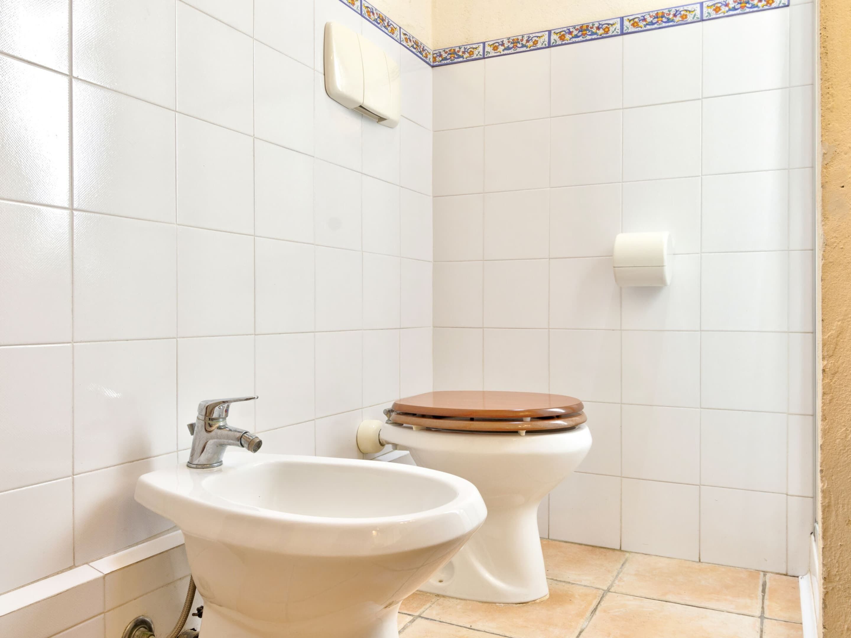 Une salle de bain avec des carreaux blancs, un lavabo et des toilettes.