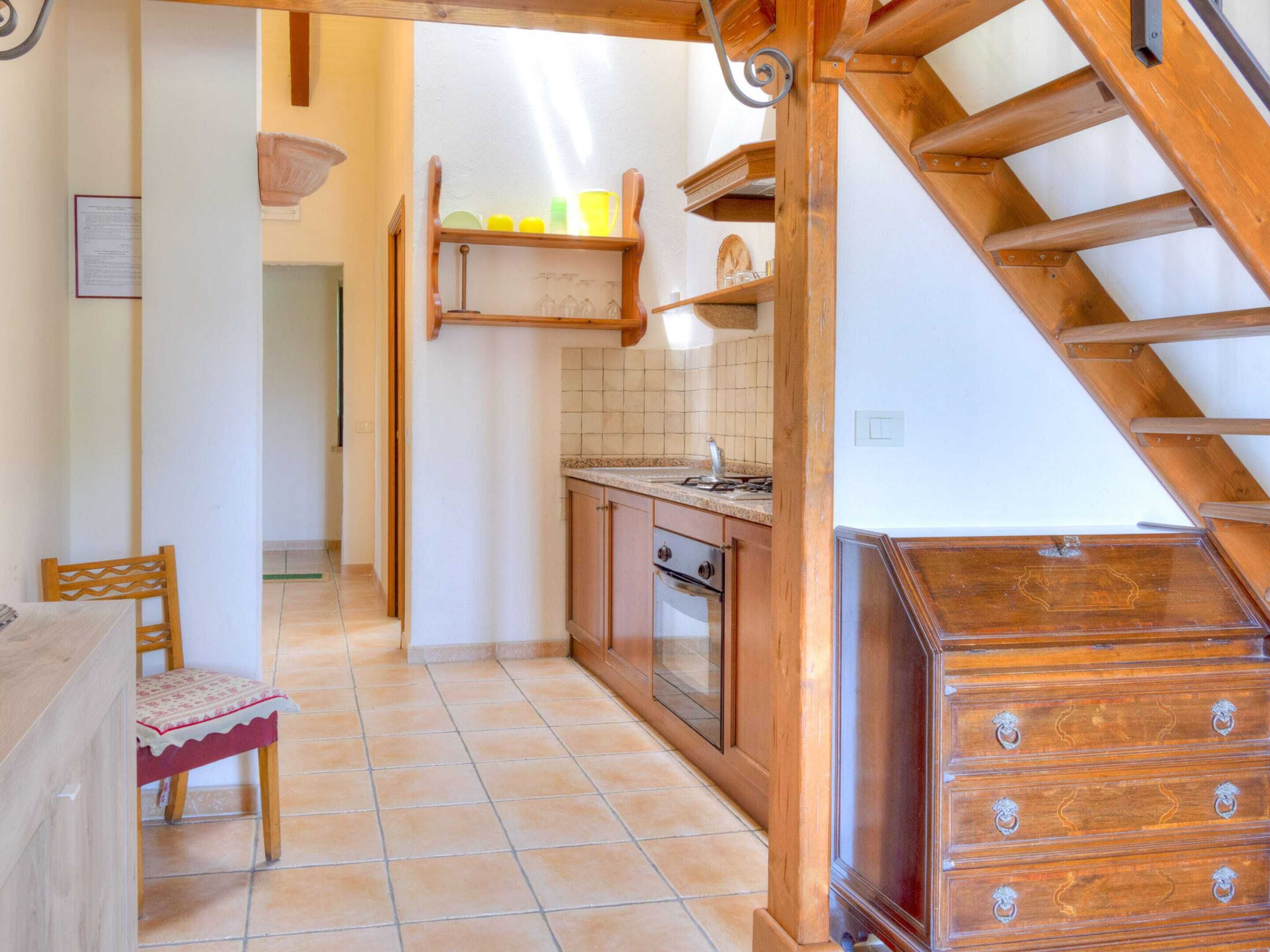 A kitchen with wooden cabinets, a tiled backsplash, and a wooden staircase.
