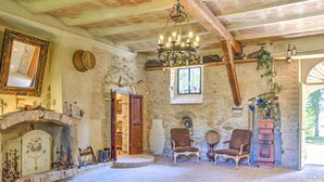 Una habitación rústica con chimenea de piedra, sillas de madera y un candelabro.