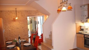 A dining area with a stone wall, a wooden table, red chairs, and a staircase leading to another level. - Holiday Home in Novigrad With Private Pool (Novigrad)