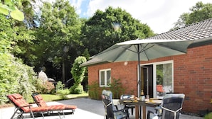 A patio with a table and chairs, a brick building, and a statue in the background. - Ferienhaus in Damshagen Nahe Ostsee (Damshagen)