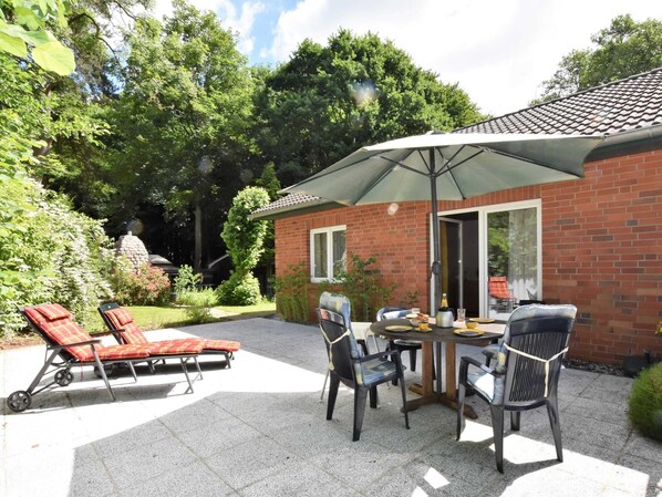 A patio with a table and chairs, a brick building, and a statue in the background.