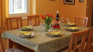 A dining table set with plates, glasses, and a bottle of wine, surrounded by chairs. - Bungalow in Borgerende-rethwisch mit Sauna (Boergerende-Rethwisch)