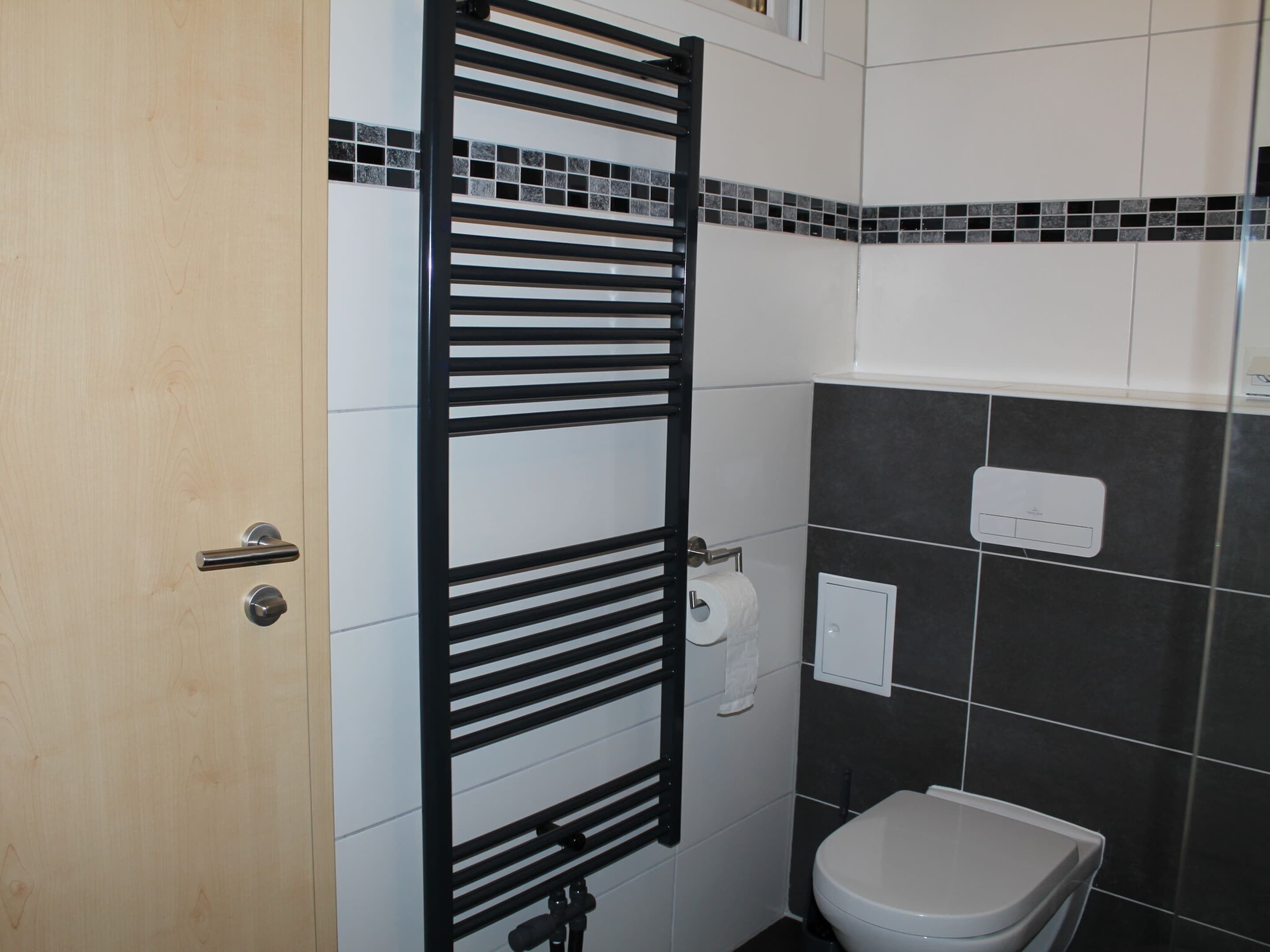 Une salle de bain avec un porte-serviettes noir, des toilettes et une porte blanche.