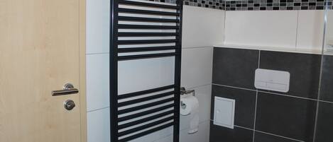 Une salle de bain avec un porte-serviettes noir, des toilettes et une porte blanche.