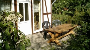 A wooden house with a patio, a table, and chairs. - Bungalow in Borgerende-rethwisch mit Sauna (Boergerende-Rethwisch)