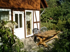 A wooden house with a patio, a table, and chairs. - Bungalow in Borgerende-rethwisch mit Sauna (Boergerende-Rethwisch)