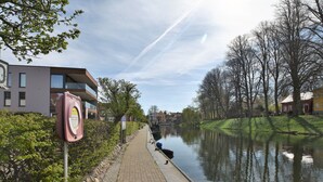 A riverside walkway with a paved path, a canal, and buildings along the riverbank. - Lovely Apartment in Plau am See Germany near Plauer Lake (Plau am See)