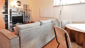A cozy living room with a sofa, a TV, a bookshelf, and a dining table. - Lovely Apartment in Plau am See Germany near Plauer Lake (Plau am See)