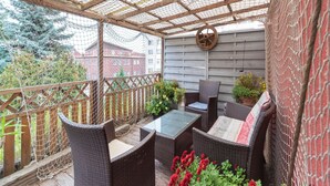 A covered outdoor seating area with wicker furniture and a wooden deck. - Apartment in Wismar Near Beach (Wismar)