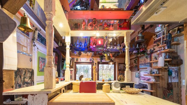 A rustic bar with wooden beams, a counter with a stove, and various bottles and decorations. - Apartment in Wismar Near Beach (Wismar)