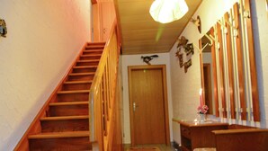 Een houten trap die leidt naar een kamer met een houten bank en een spiegel.