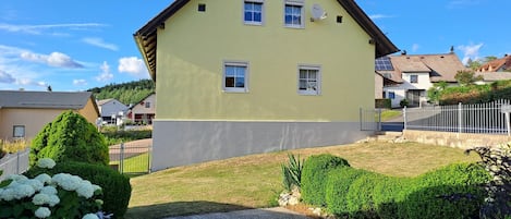 Una casa de dos pisos con techo plano, una antena parabólica y un camino de entrada pavimentado.