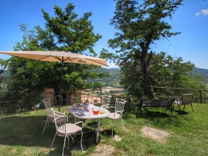 An outdoor dining area with a table and chairs, surrounded by trees and a scenic view of hills. - Farmhouse in Umbertide Near Lake Trasimeno (Umbertide)