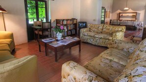 A living room with a sofa, a coffee table, a bookshelf, and a television. - Farmhouse in Umbertide Near Lake Trasimeno (Umbertide)