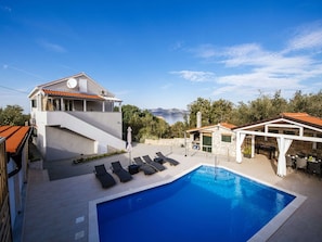 Une villa moderne dotée d’une piscine, d’un espace salon extérieur et offrant une vue panoramique sur la mer.