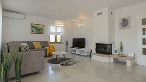 Una sala de estar moderna con sofá, televisión, chimenea y plantas decorativas.