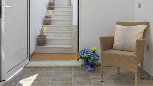 A hallway with a wicker chair, a vase with flowers, and a staircase leading to a room. - Casa Bianca Villa in Kolympia (Kolympia)